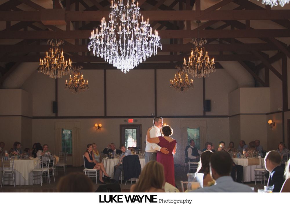 Woman embracing another, both smiling; indoors, event setting.