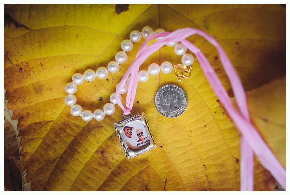 Pearl necklace with a pendant and a coin resting on a yellow leaf.