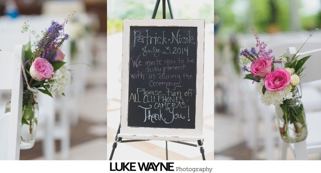 Wedding sign on an easel, surrounded by flower arrangements on chairs.