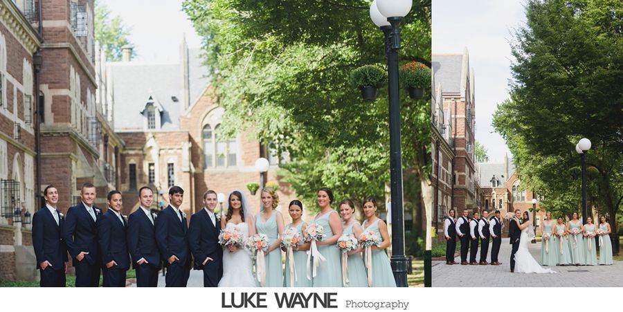 Wedding party poses outside brick building, couple with bridal party. Mint dresses, navy suits. Sunny day.