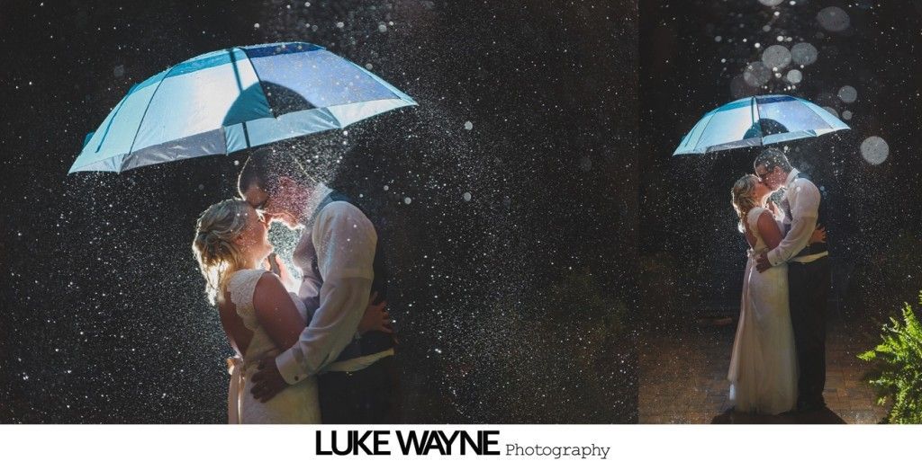 Wedding couple kissing under an umbrella in the rain.