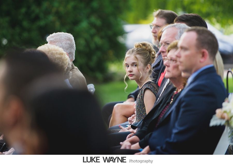 Guests seated at an outdoor event, a young girl glances towards the camera.
