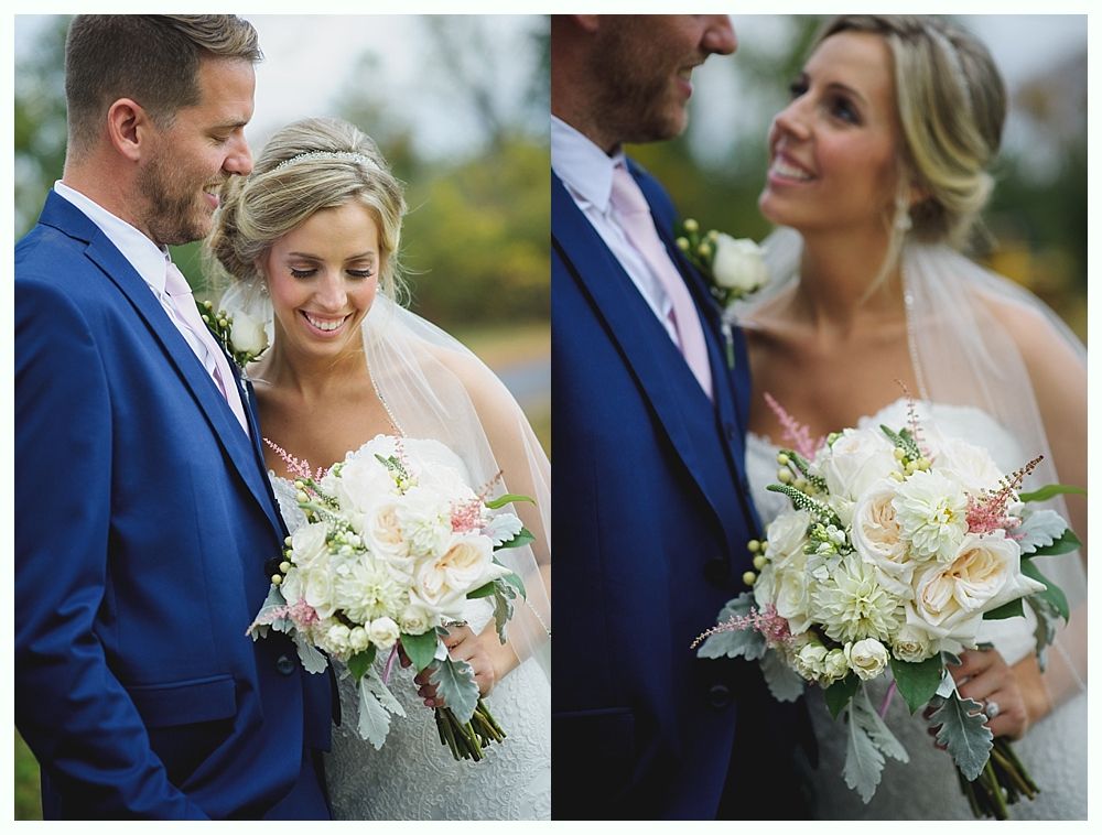 Bride and groom embracing, the bride holding a bouquet of white flowers. The groom wears a blue suit, the bride a veil.