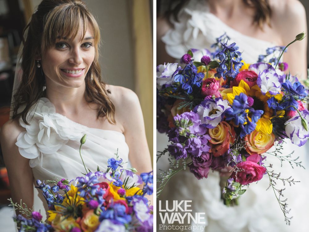 Couple gazing at each other and smiling; woman's hair blowing; outdoor setting with blurry background.