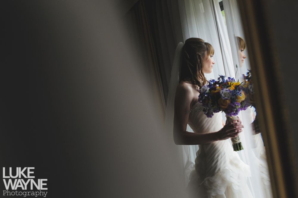 Black and white landscape with a dark, cloudy sky over a field. Sunbeams filter through the clouds.