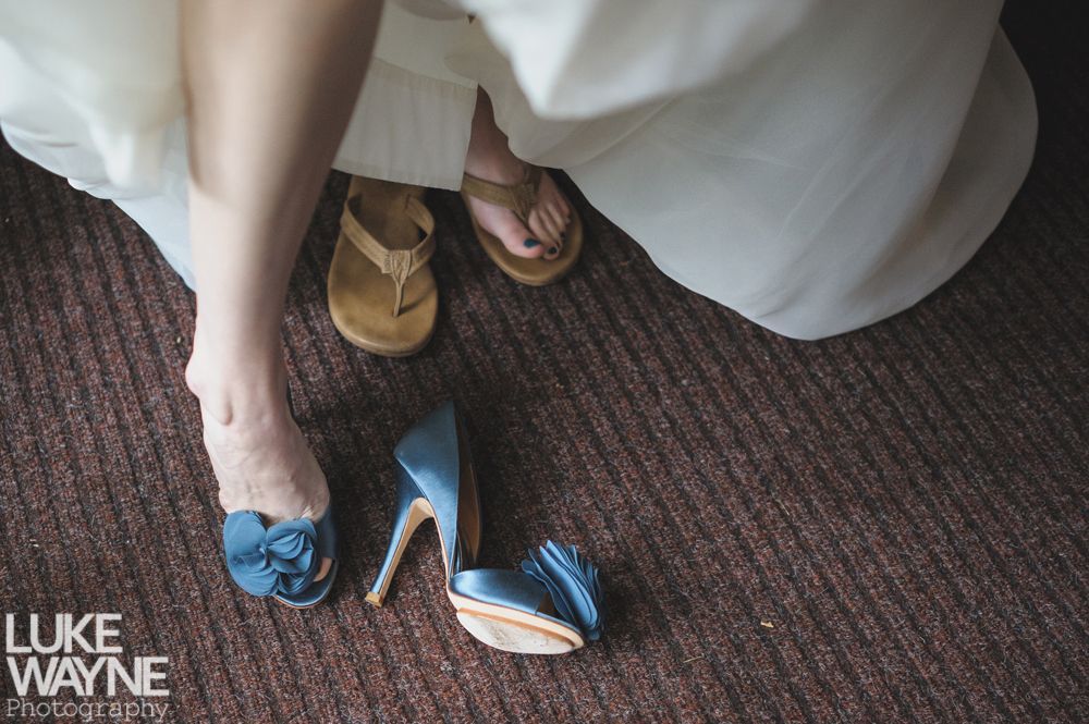 Couple sits on a rocky outcrop, distant building visible. He wears a blue jacket, she wears an orange skirt. Outdoors.