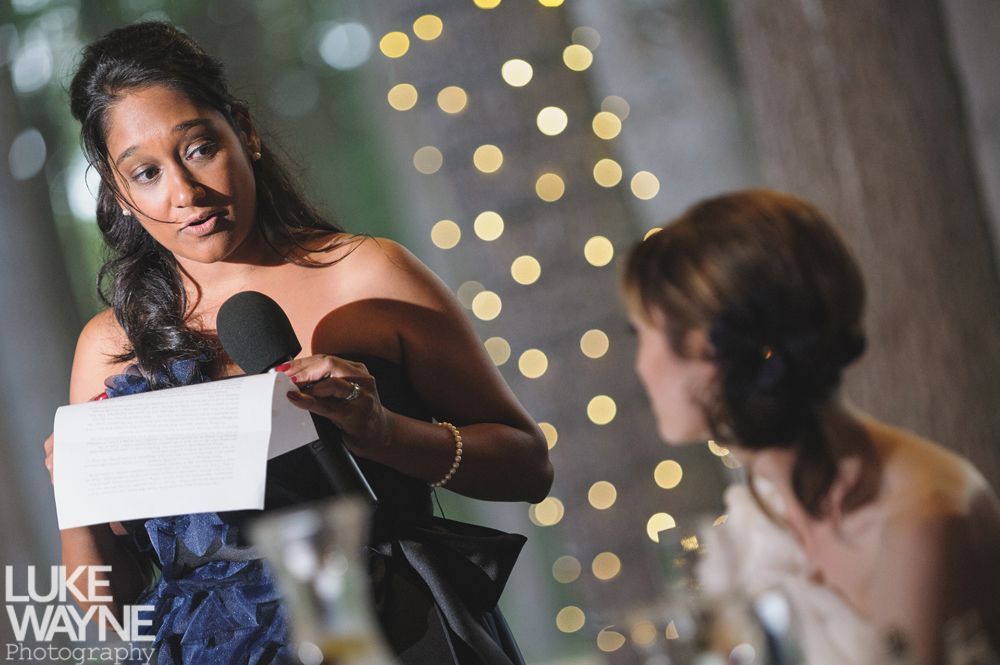 Couple embracing at sunset; man in green shirt, woman in denim jacket and red dress, with blowing hair.