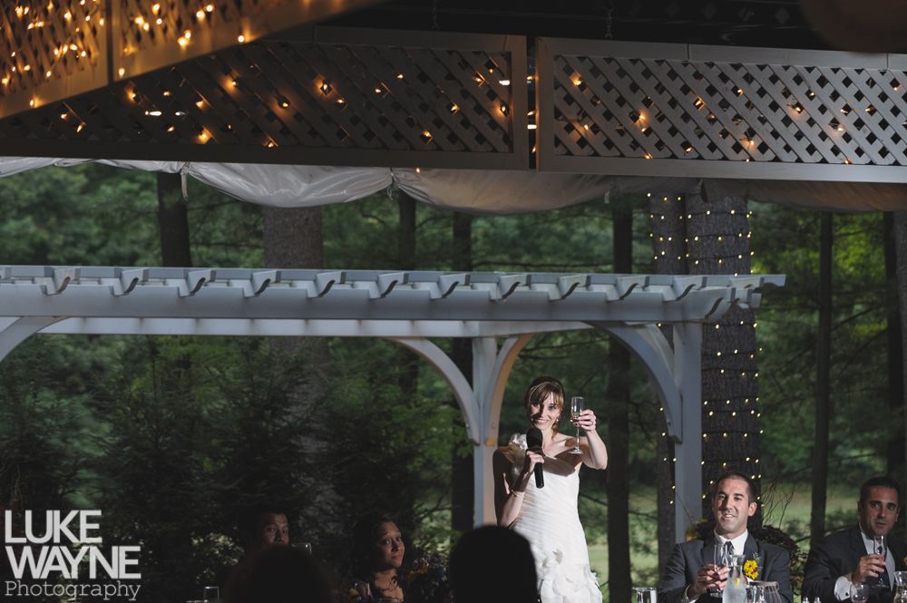Couple embracing at sunset; man in green shirt, woman in denim jacket and red dress, with blowing hair.