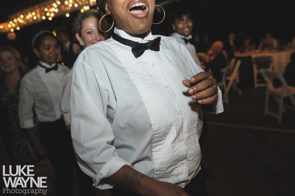 Couple embracing at sunset; man in green shirt, woman in denim jacket and red dress, with blowing hair.