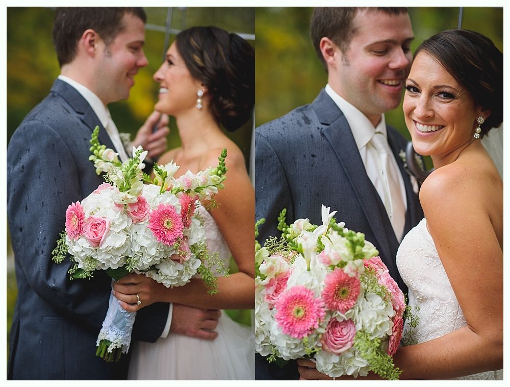 Bride and groom embrace in the rain, holding a bouquet. She smiles; he gazes at her.