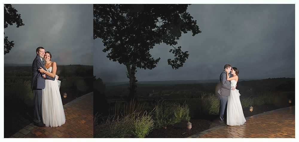 Wedding couple embracing outdoors under a dark, stormy sky.