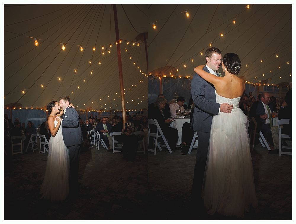 Bride and groom dance under string lights in a tent at wedding reception.
