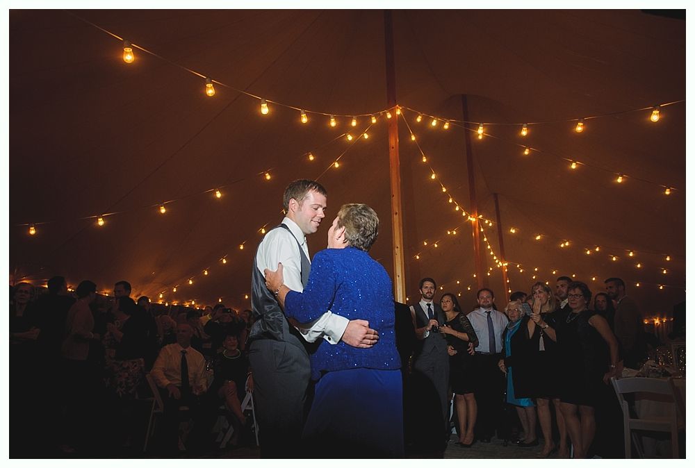 Man and woman dancing under string lights at a wedding reception.