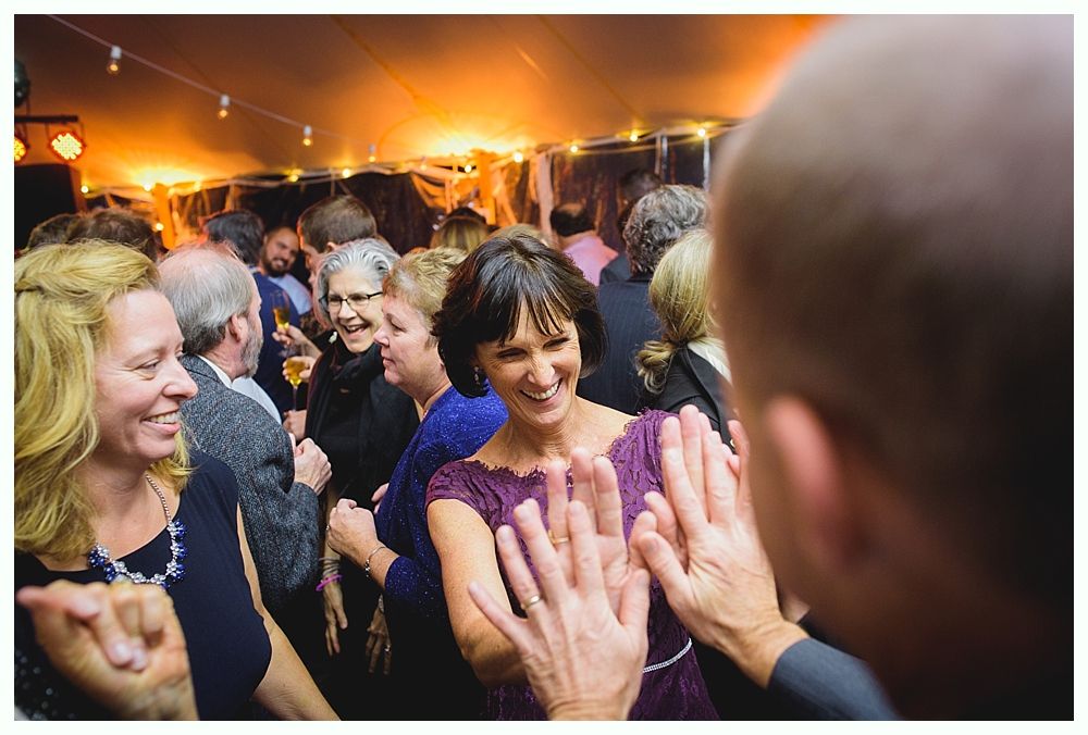 People dancing at a party under warm lighting; they are smiling and clapping hands.
