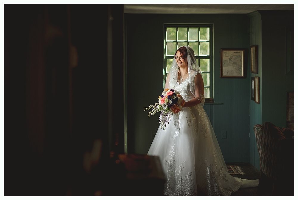 Couple embraces under a tree with intertwined branches, soft focus around them.