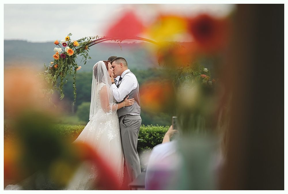 Diamond engagement ring on yellow flower in tall grass.
