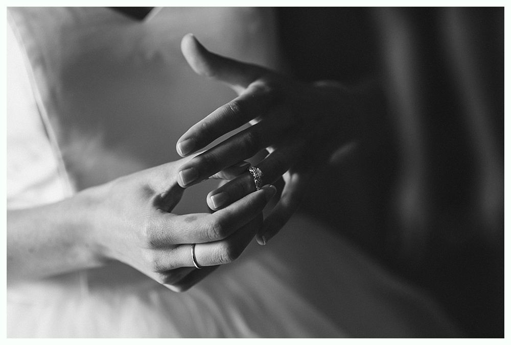 Hands putting on a ring; black and white.