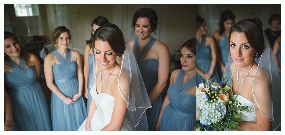 Bride smiles with bridesmaids in blue dresses, holding bouquet.