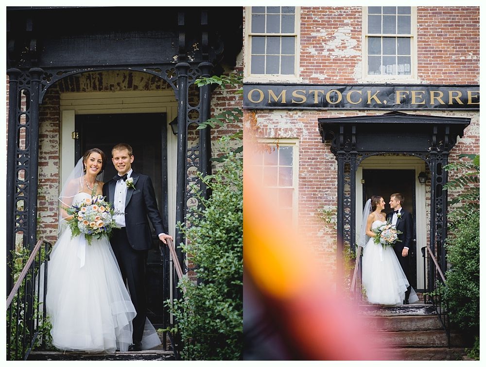 Wedding couple, bride in tulle gown and groom in a tuxedo, smiling at the entrance of a brick building.