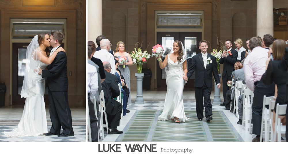 Bride and groom kiss, then walk down aisle together, guests cheer. Elegant indoor ceremony with columns.