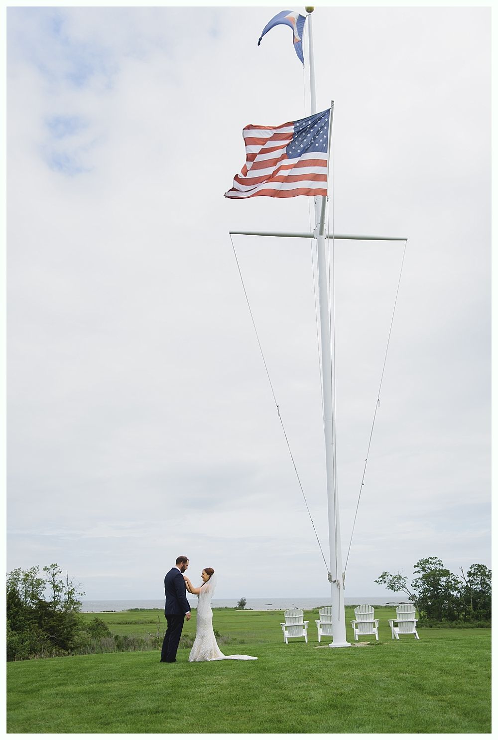 Couple at outdoor wedding ceremony with American flag and tall white mast.