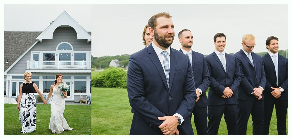 Bride and her mother walk toward groom and groomsmen on lawn. Seaside house in background.