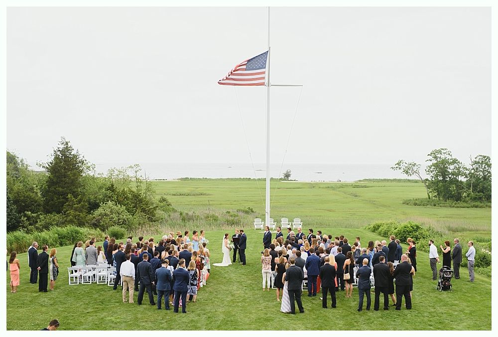 Wedding ceremony outdoors with guests and American flag.