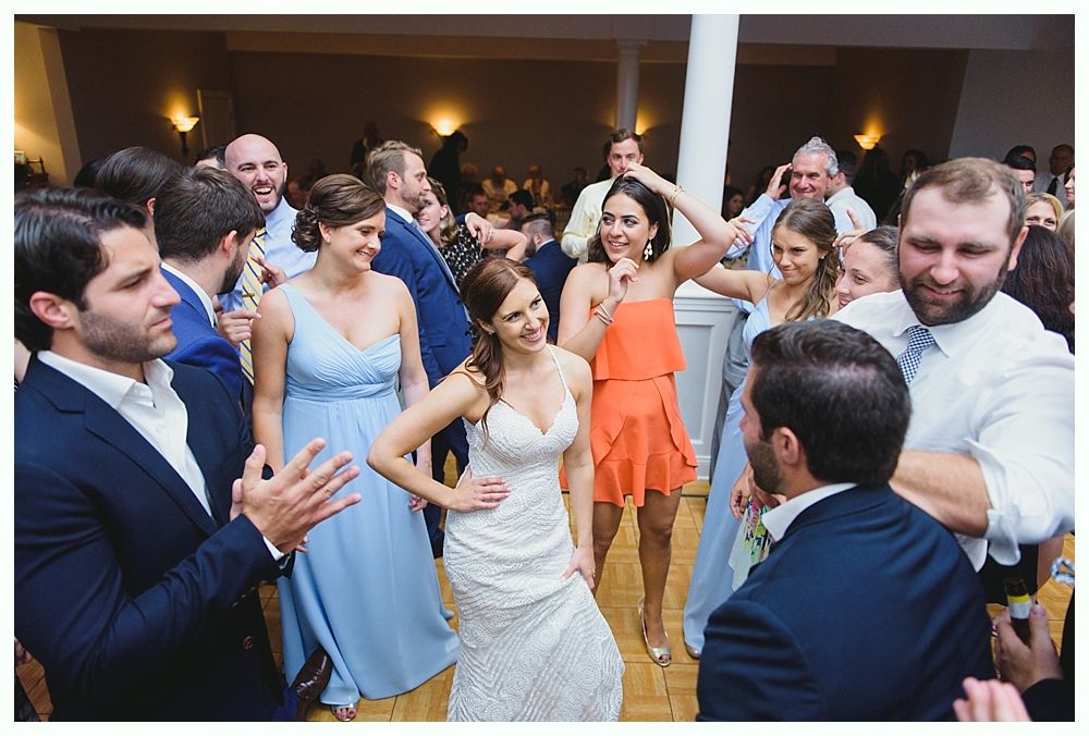 Wedding reception: Bride dances, surrounded by guests in a festive ballroom with lights.