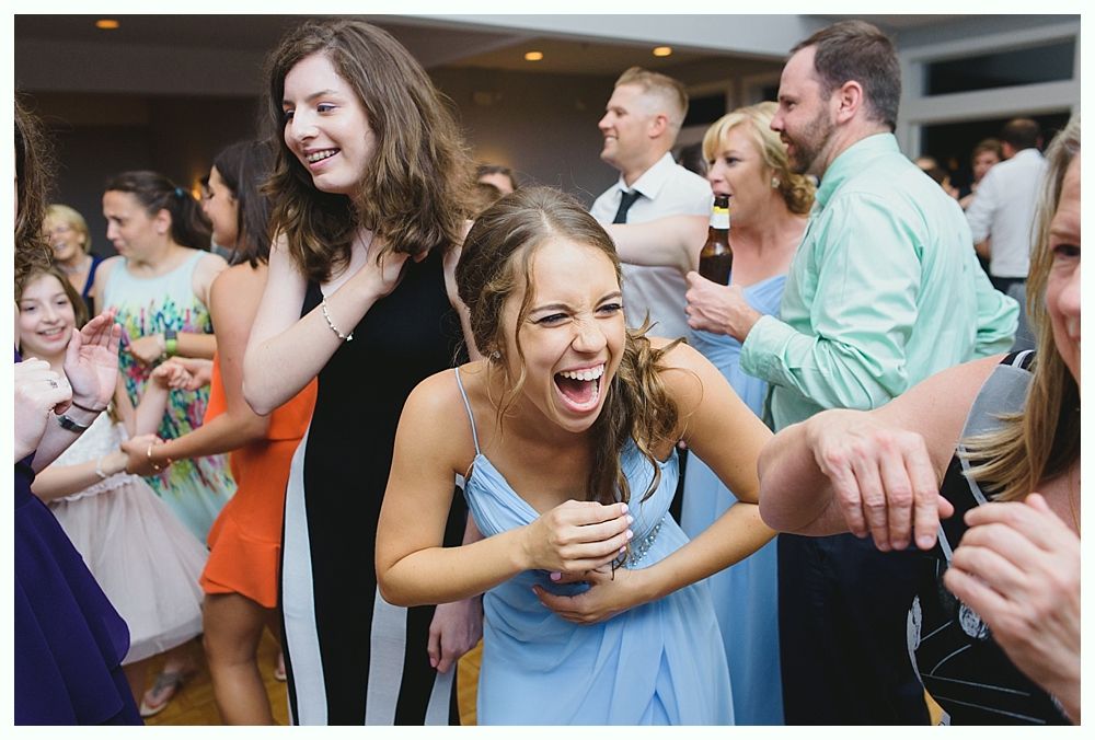 People dancing and laughing at a party, inside a brightly lit room.