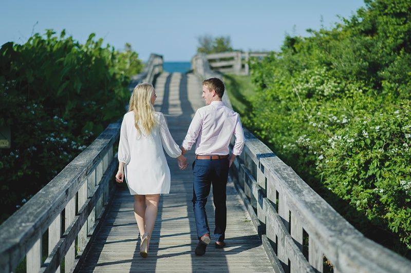 Couple in formal attire; the woman in a red sari, the man in a vest and tie; outdoors.