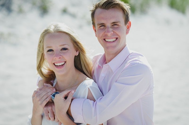 Couple in formal wear looking at each other; woman wearing red sari and gold earrings, man in a black suit.