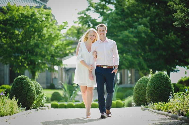 Couple kissing under a large tree, silhouetted against a setting sun on a grassy field.