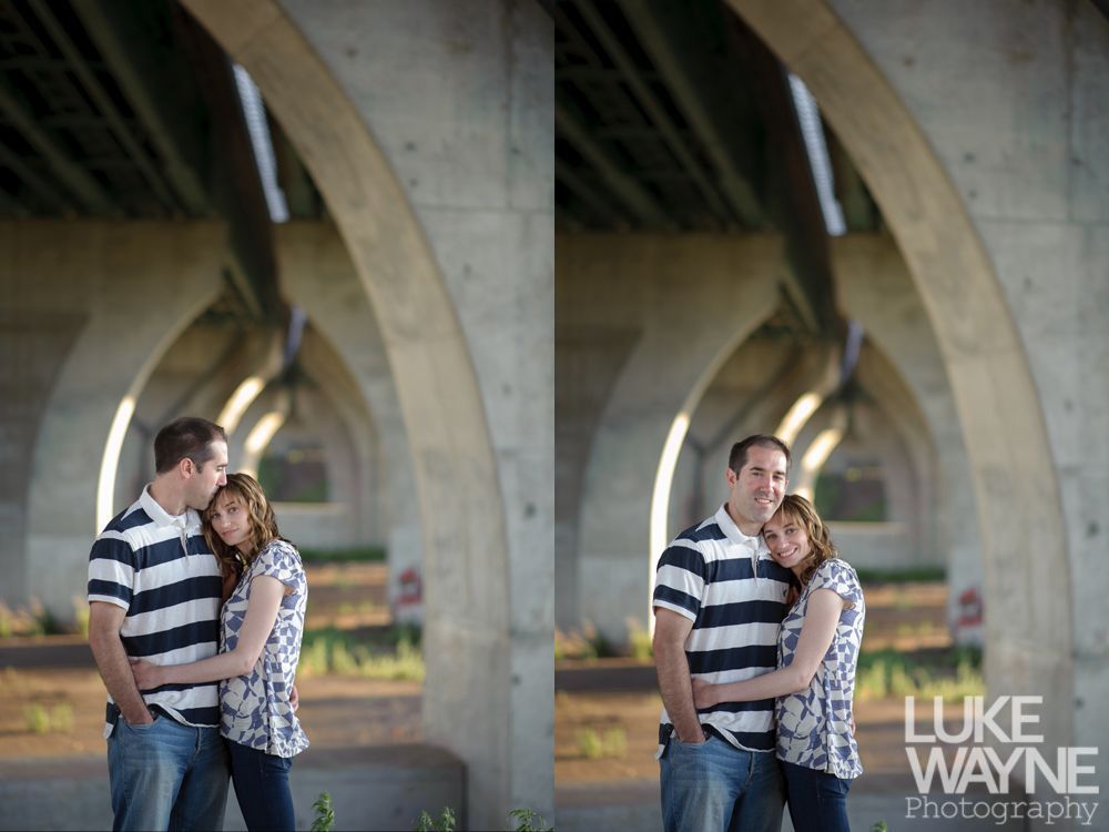 Couple embracing under a concrete bridge with arched supports, one looking at the other, outdoors.
