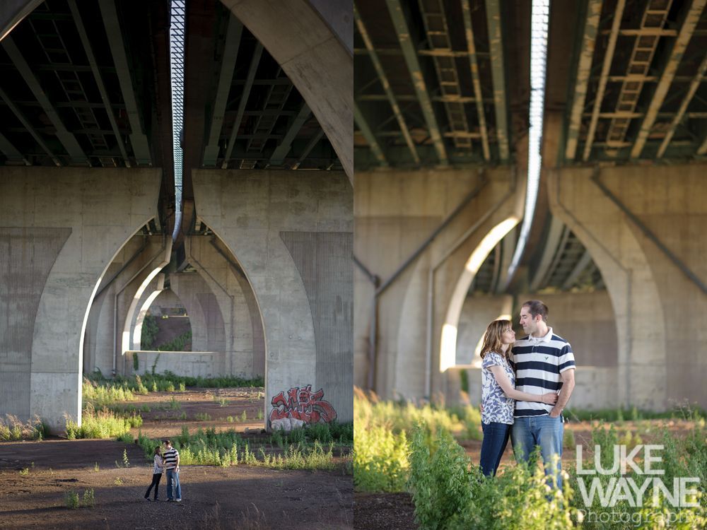 Couple under a bridge; light streams through archways. They stand in tall grass, embracing.