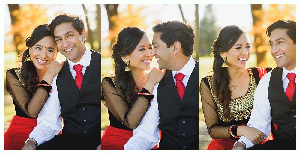 Couple in formal attire, smiling, close together, outdoors with autumn foliage.