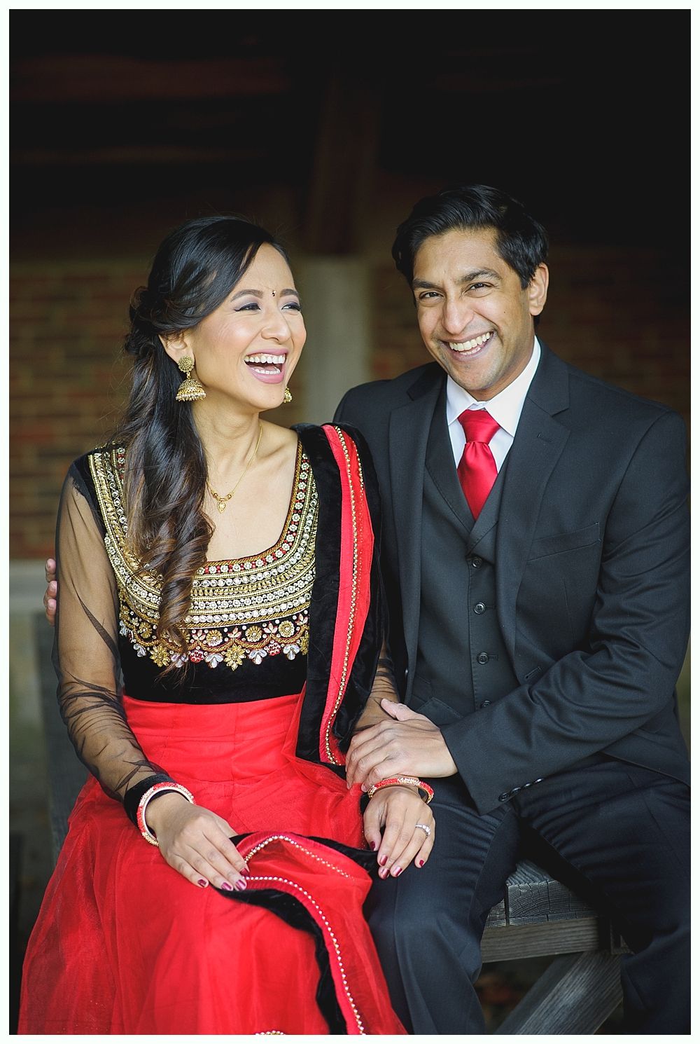 Couple laughing together. Woman in red sari, man in suit with red tie.