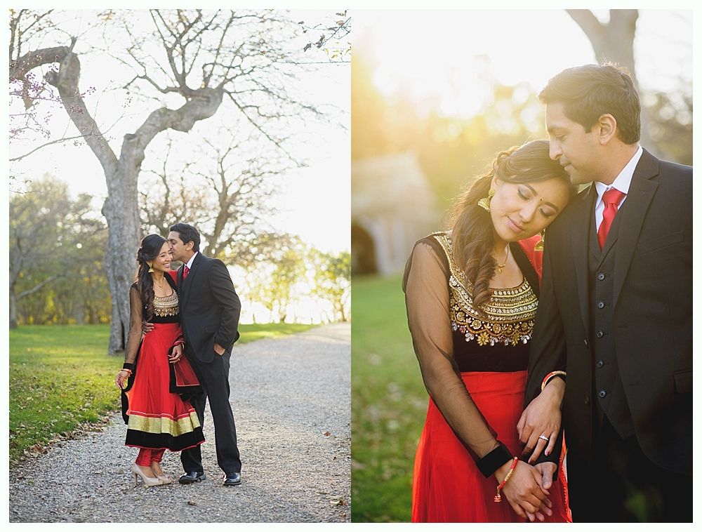 Couple in formal attire, posing outdoors in a park. Woman in red and gold traditional dress, man in a suit.