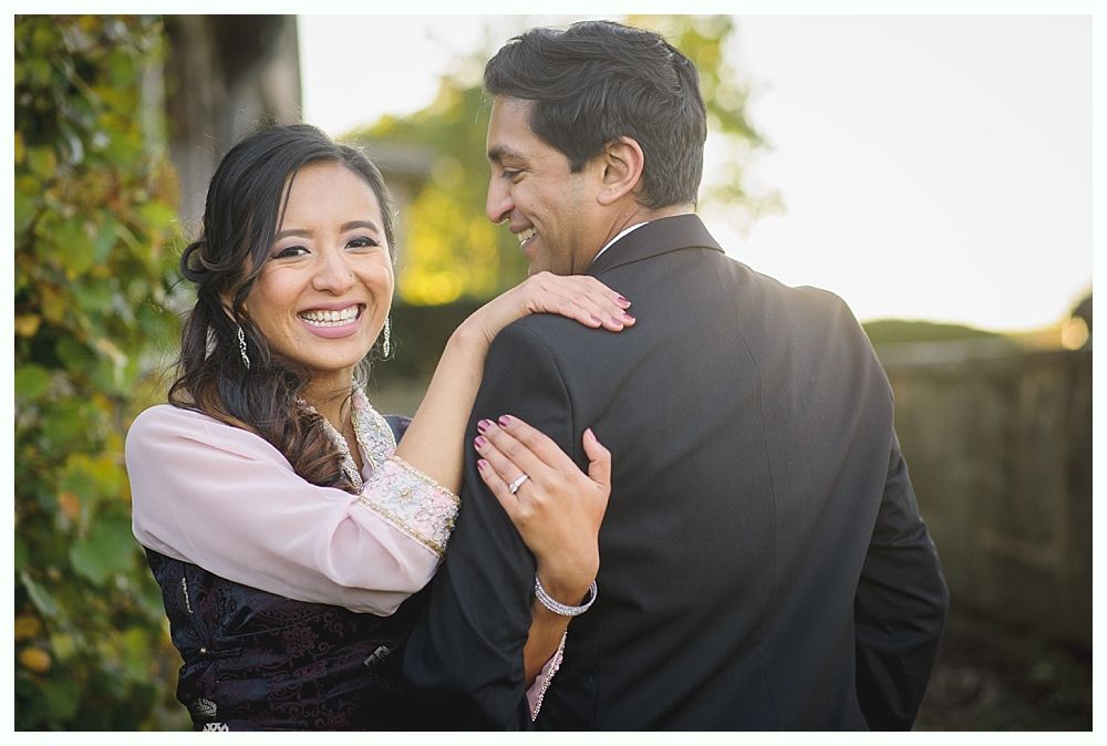 Woman smiling, arm around man's shoulders; both are outdoors.