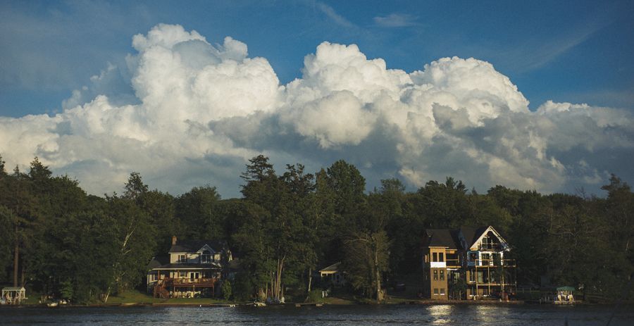 Couple kissing near trees at night with glowing streetlights in foreground.