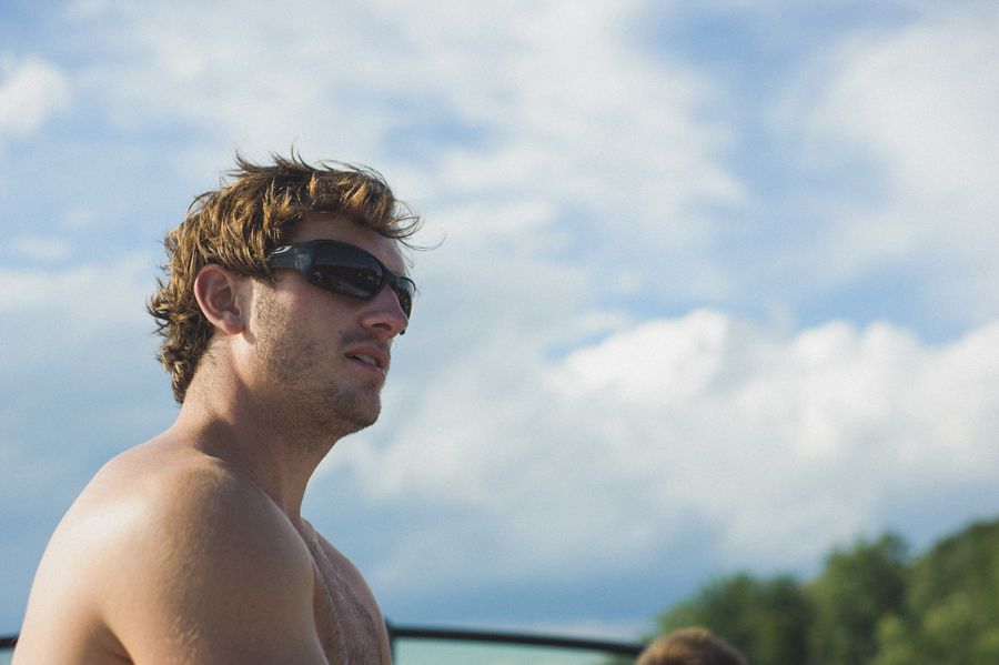 Bride and groom embrace, lit by spotlight against dark night sky and hillside.