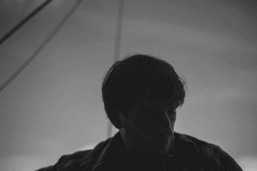 Person taking photo in mirror, indoors; black and white.