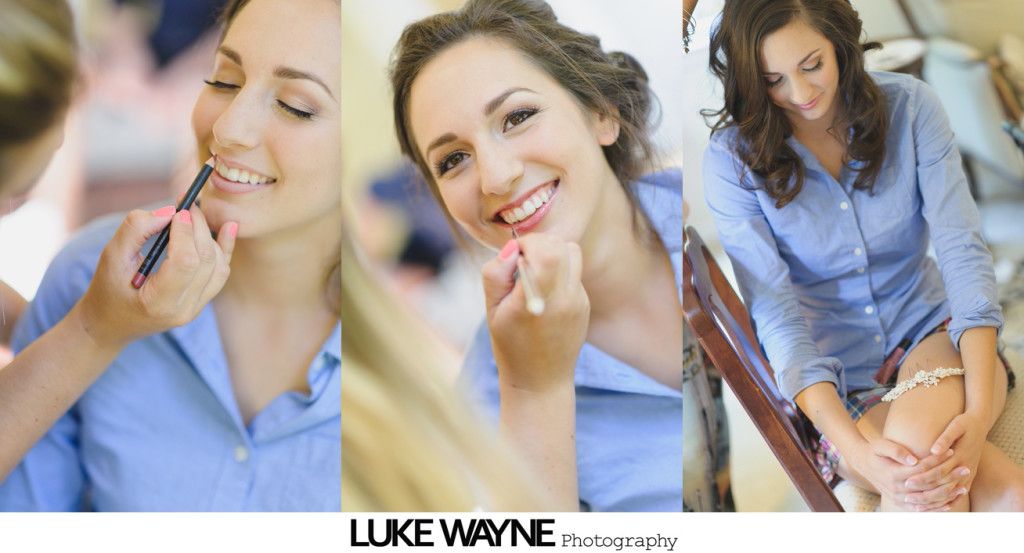 Woman getting makeup applied, smiling, wearing blue shirt; getting ready for a wedding.
