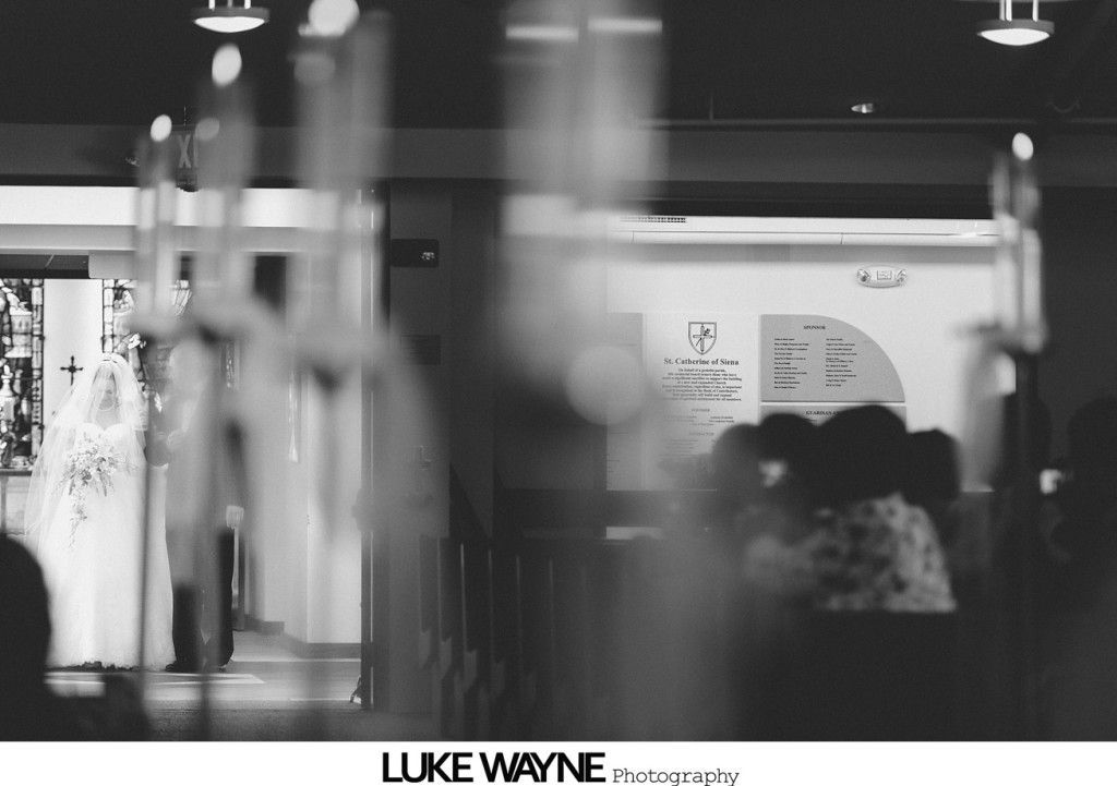 Two brides in white dresses embracing, smiling, outdoors.