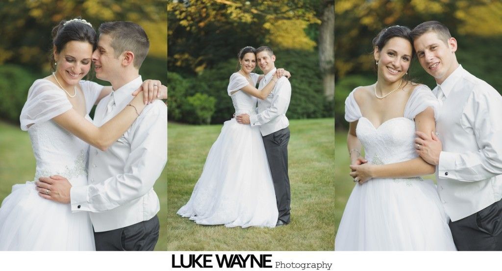 Bride and groom embracing in a grassy setting. Bride in white dress, groom in white shirt and dark pants.