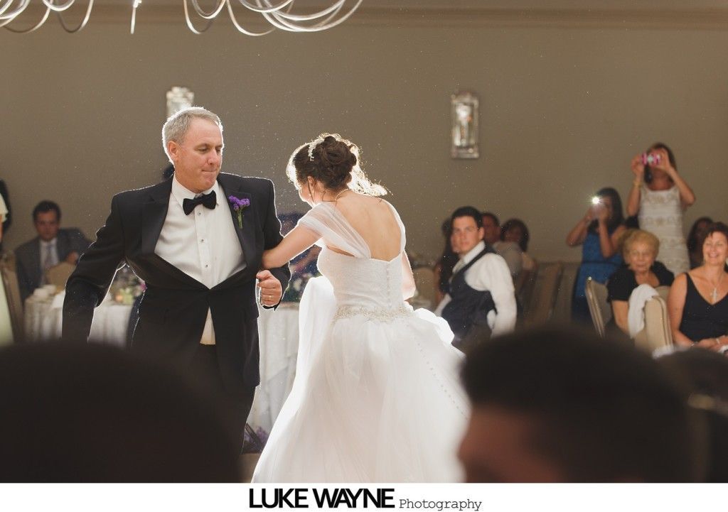 Bride dances with a man in a tuxedo at a wedding reception.