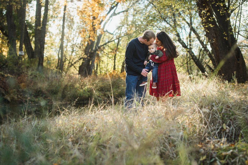 Family, parents and child, in an autumn field, kissing.