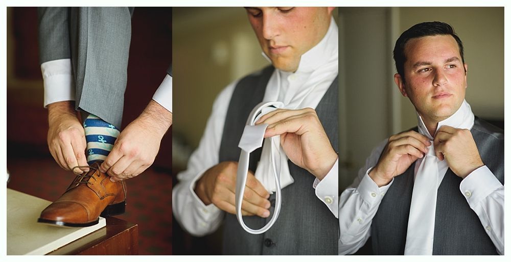 Man in gray suit and tie, preparing to put on shoes, tying tie, focused expression.