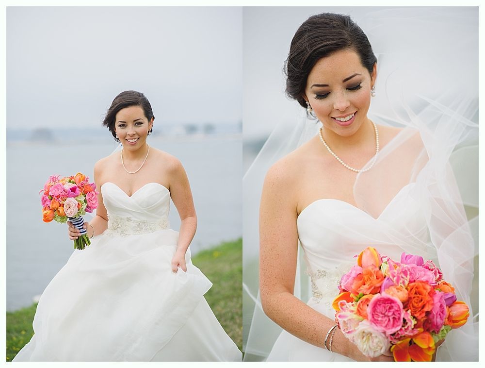 Bride in strapless white gown, holding a colorful bouquet, smiling outdoors.