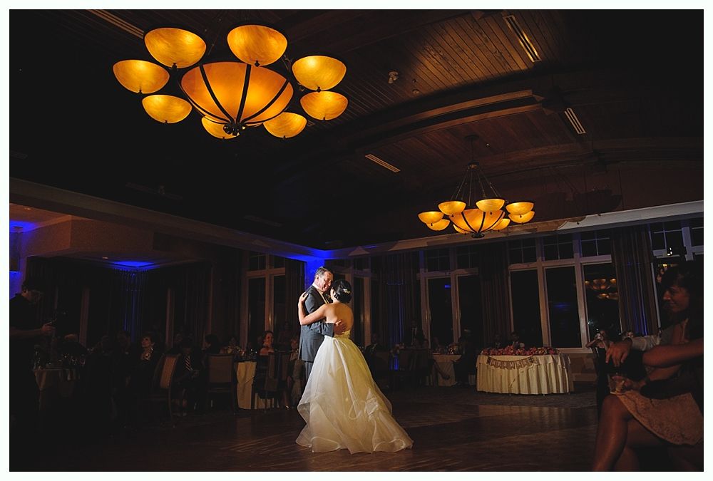 Couple dancing at a wedding reception under decorative chandeliers.