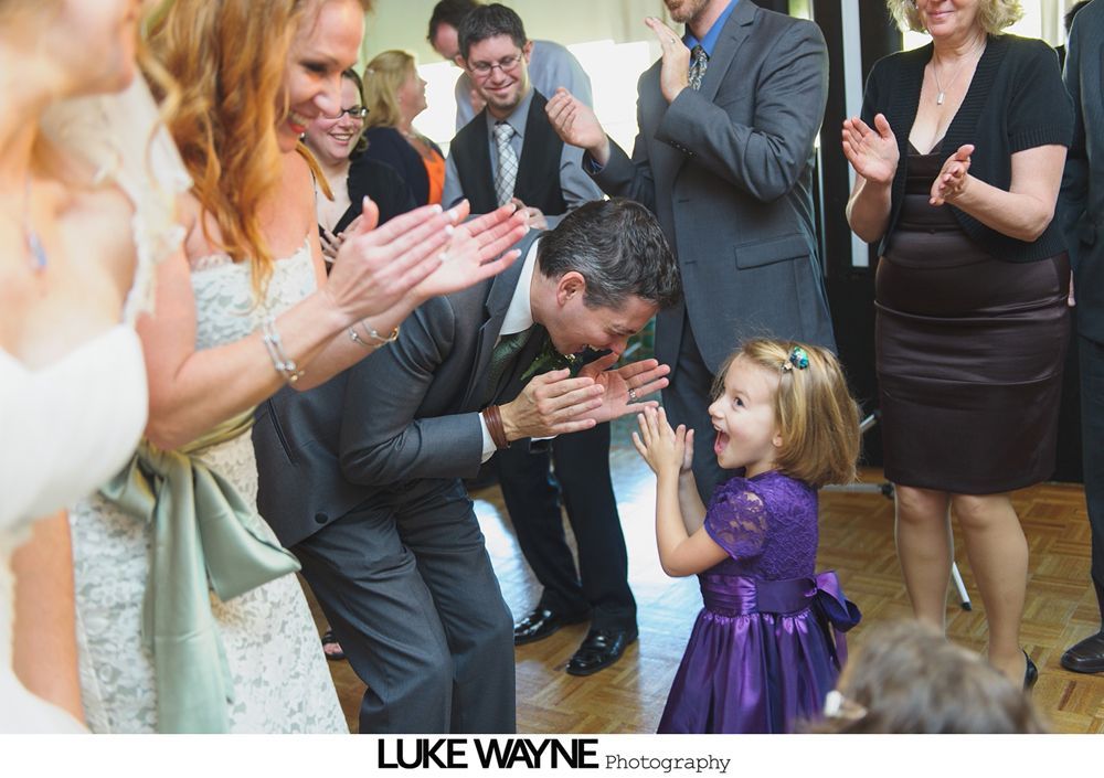 Wedding reception with dancing; bride in a white gown and guests in colorful dresses on a dance floor.